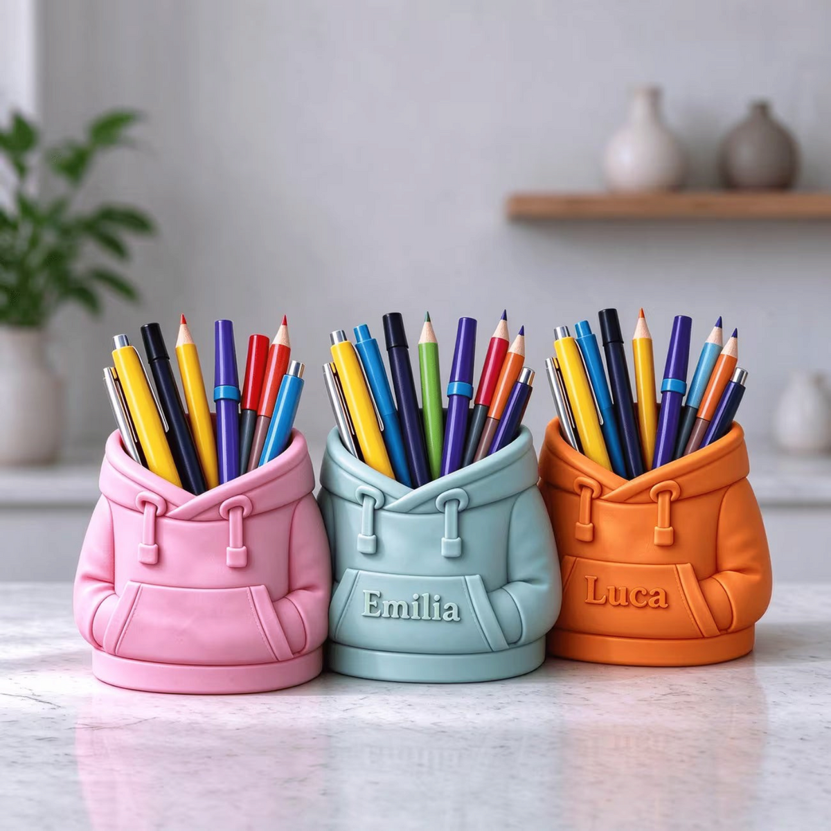 Elite Stationery House personalized 3D printed hooded sweatshirt pen holders in pink, light blue, and orange.